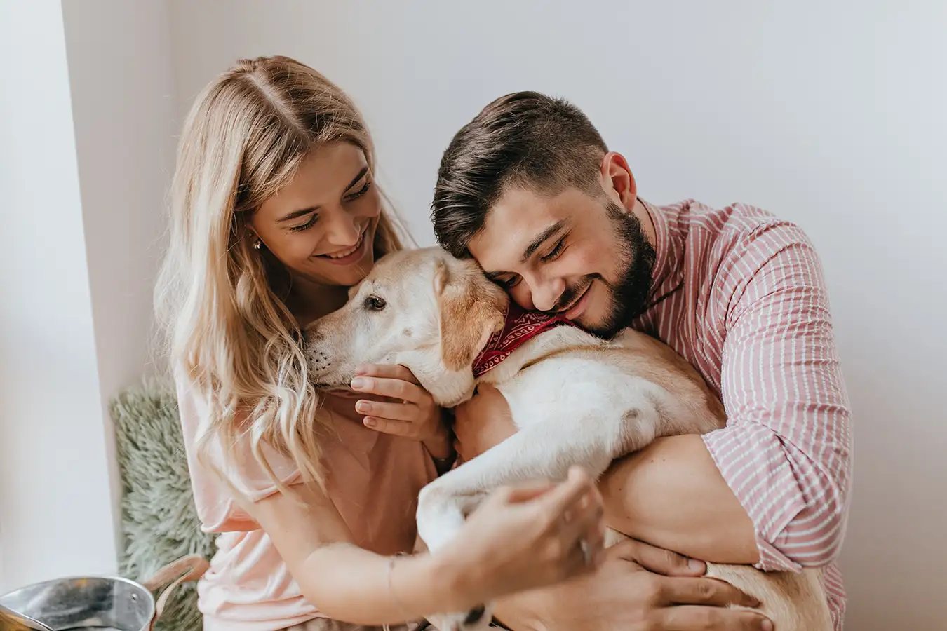 Pareja abrazando a su perro con cariño en casa
